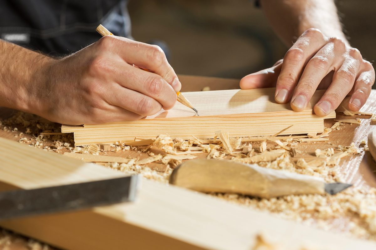 Ebanista marcando a lápiz una tabla de madera antes de cortar