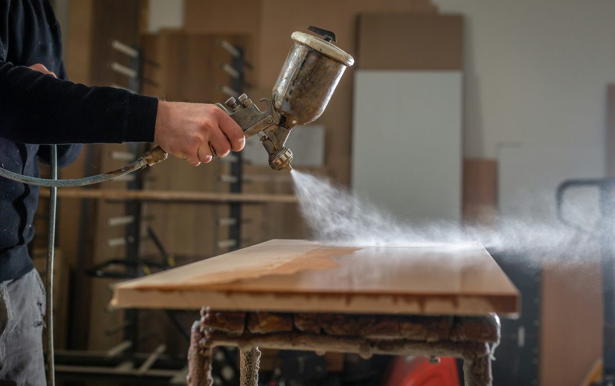 Lacado a pistola de un tablero de madera en el taller